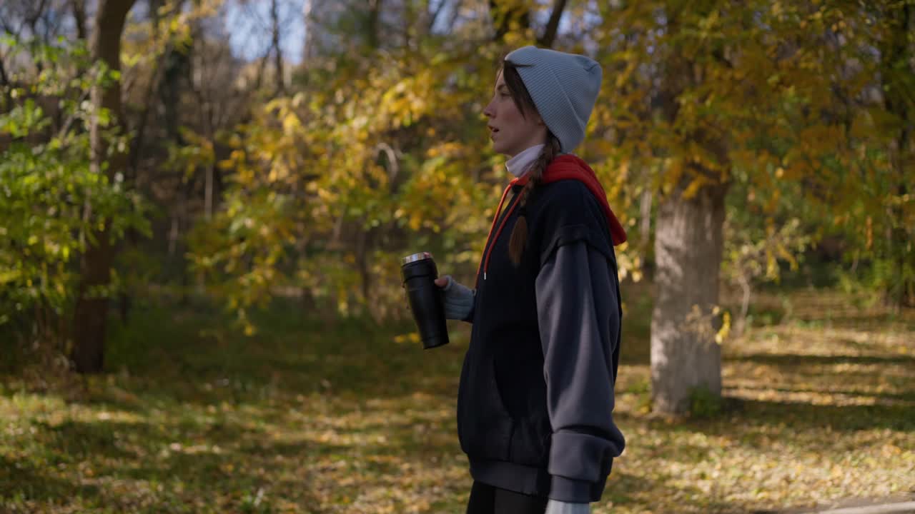커피 컵 을 들고 가을 공원 에서 고 있는 여자