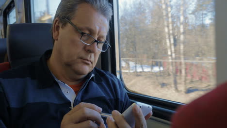 senior man surfing the internet on cellphone in train