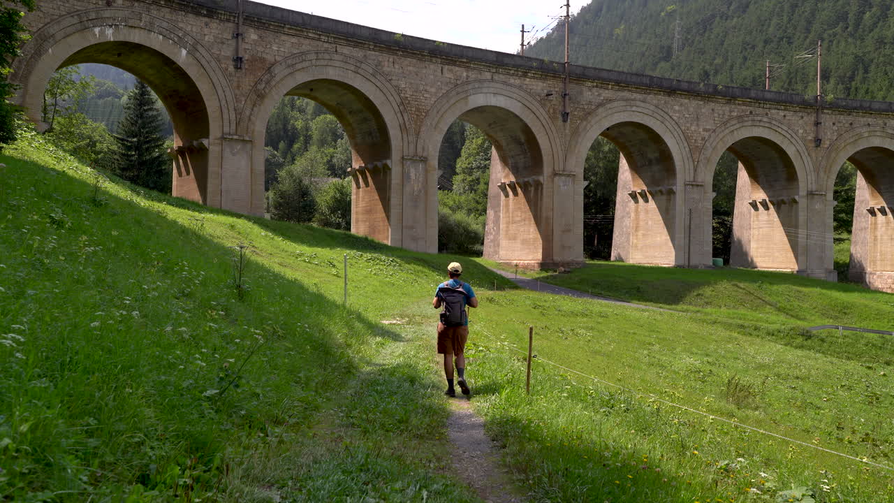 excursionista masculino caminando por el paisaje con acueducto en semmering, austria