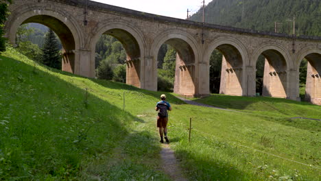 male hiker walking through landscape with aqueduct in semmering, austria