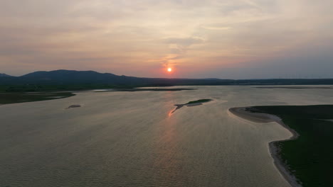 aerial shot of serene sunset over a tranquil lake with surrounding greenery