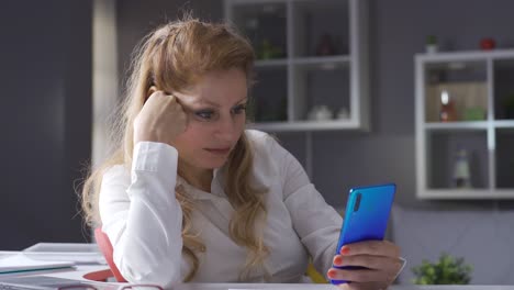 Elderly-businesswoman-working-in-home-office-looking-at-her-phone.-Using-social-media.