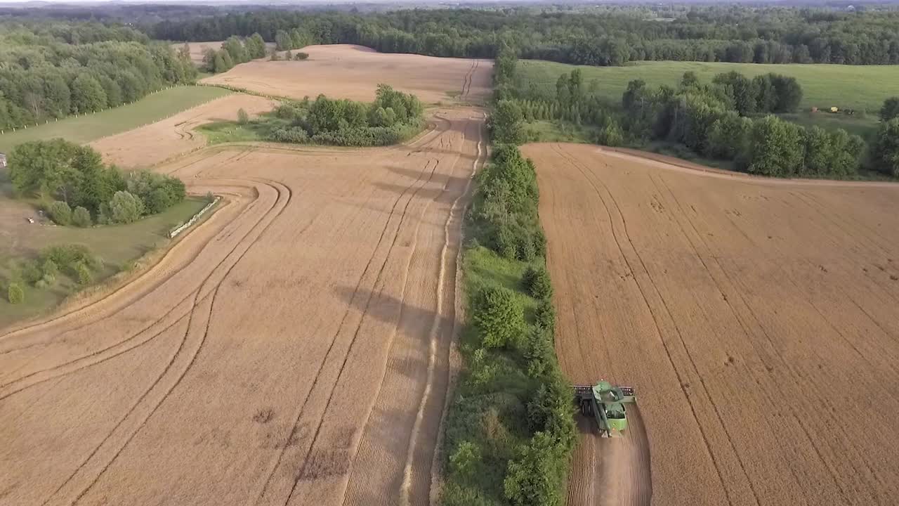 Aerial View Flying Over Combine Harvester In Rural Countryside During Sunset In Slow Motion
