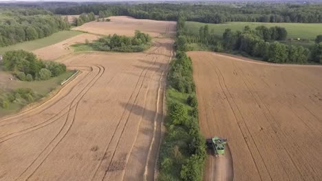 Luftaufnahme,-Die-Während-Des-Sonnenuntergangs-In-Zeitlupe-über-Mähdrescher-In-Ländlicher-Umgebung-Fliegt