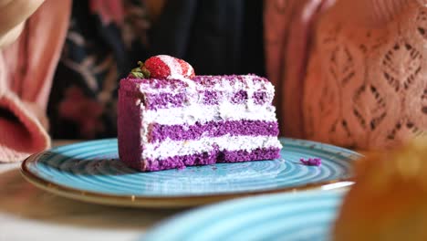 woman eating a slice of purple cake with strawberries