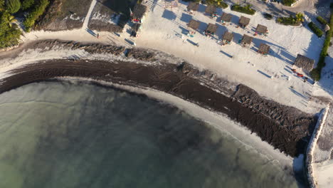 Sandy-beach-with-deck-chairs-and-black-sand-washed-by-small-waves