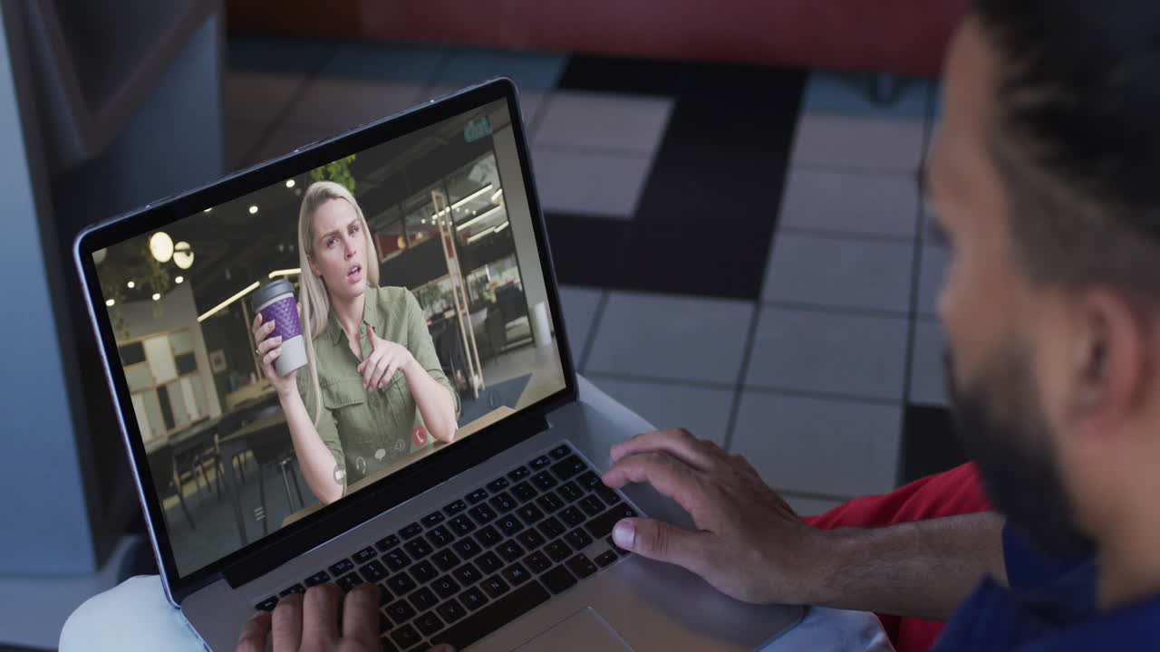 hombre de oriente medio haciendo una videollamada con una colega de oficina en una computadora portátil