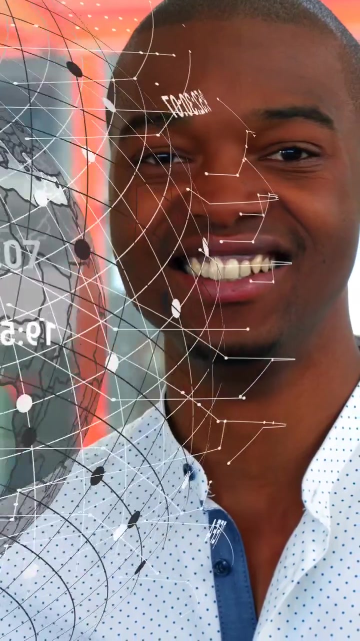 Vertical video: Smiling man in dotted shirt watching rotating globe and HUD revealing face by glass