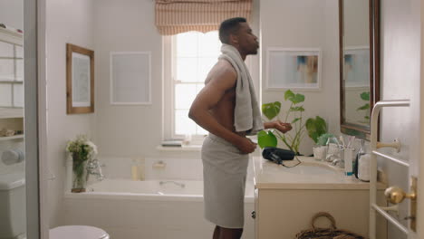 happy-african-american-man-dancing-shirtless-in-bathroom-looking-in-mirror-having-fun-morning-routine-getting-ready-enjoying-positive-self-image-doing-silly-dance-celebrating-success