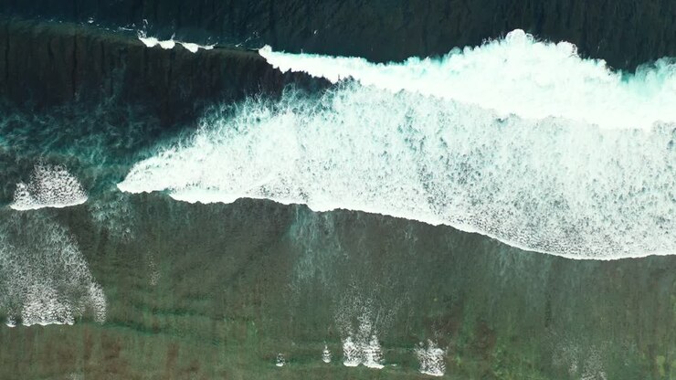 Dramatic seaside with white ocean waves splashing on colorful shore of tropical island with coral reefs and pebbles, Hawaii