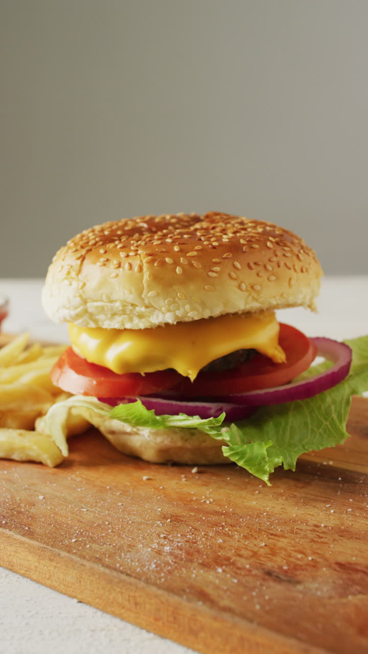 video vertical de una hamburguesa casera fresca con ensalada en una tabla de cortar de madera