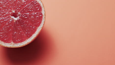 video de pomelo rojo cortado con espacio de copia sobre fondo naranja