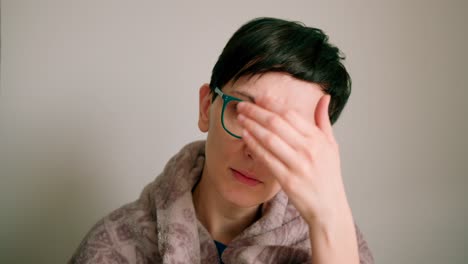 close up view of a women wearing glasses checking her forehead for illness symptoms