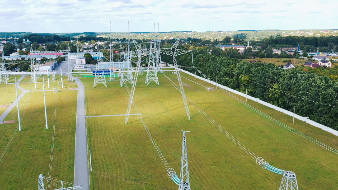Electricity pylons in the countryside. Power station with white tall towers on field. Distribution of electricity. Motion camera back.