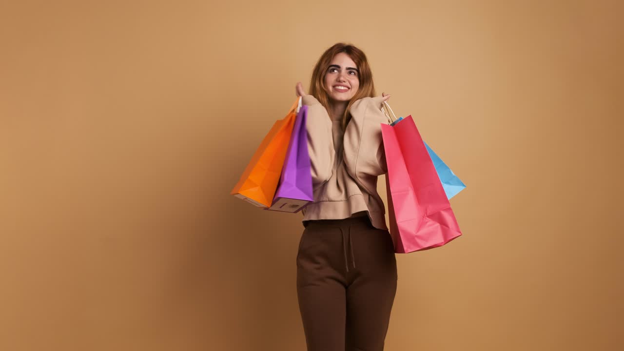 Stylish female shopaholic with colorful paper bags in studio