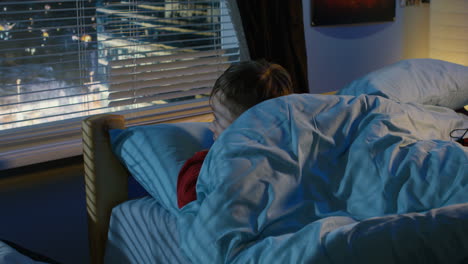 boy looking out the window at night