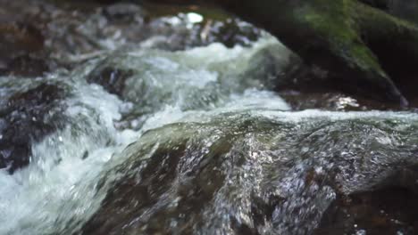 follow shot of water flowing over rock at waterfall in slow motion