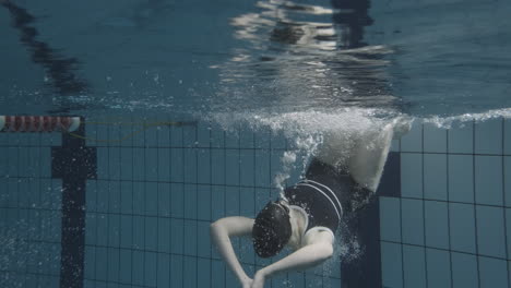 underwater shot of a young female swimmer coming to the edge and turning around to continue swimming