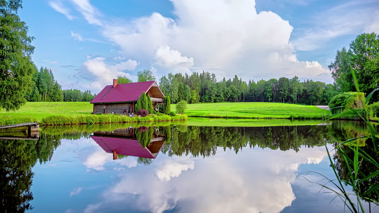 자연 속에 집과 호수가 있는 농장에서 흰 구름의 어두운 폭풍우가 몰아치는 구름으로의 저속 촬영