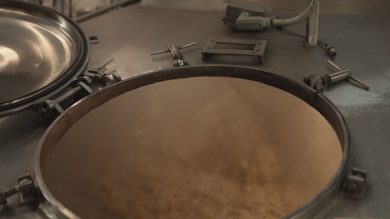 Beer mixes in a steel brewing fermentation vat inside a craft brewery slider shot slow push in