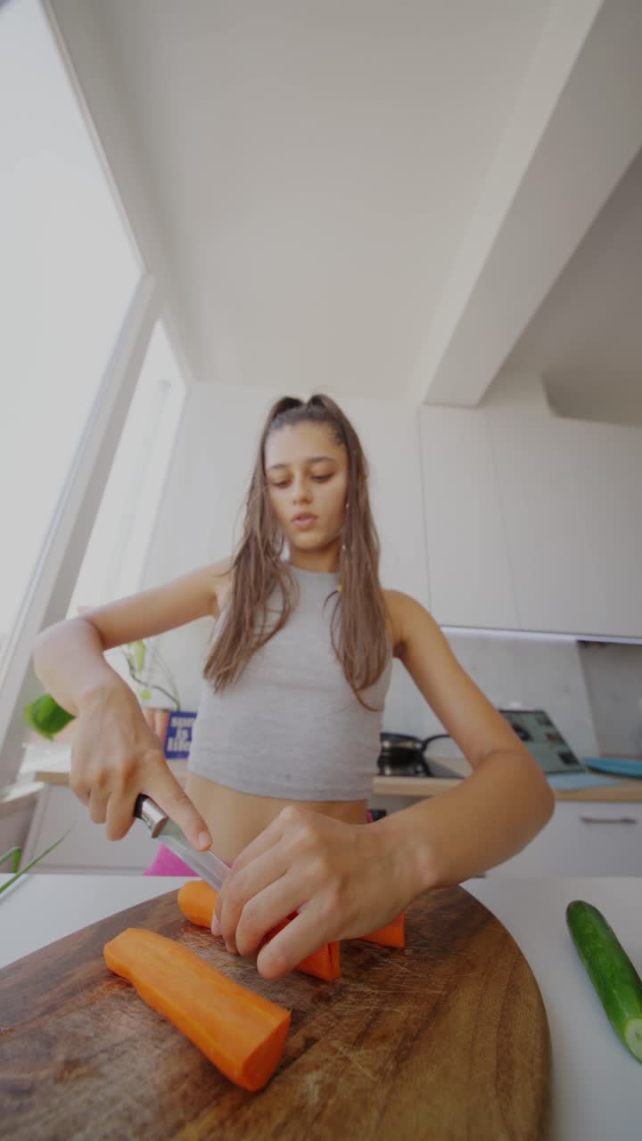 Young Woman Chopping Carrots in the Kitchen