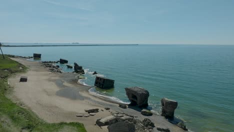 Beautiful-aerial-establishing-view-of-Karosta-concrete-coast-fortification-ruins,-calm-Baltic-sea,-sunny-summer-day,-wide-drone-shot-moving-forward