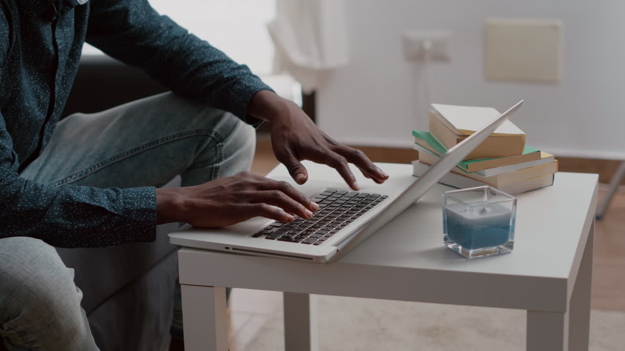 Close up black man hands browsing using laptop computer, searching social media