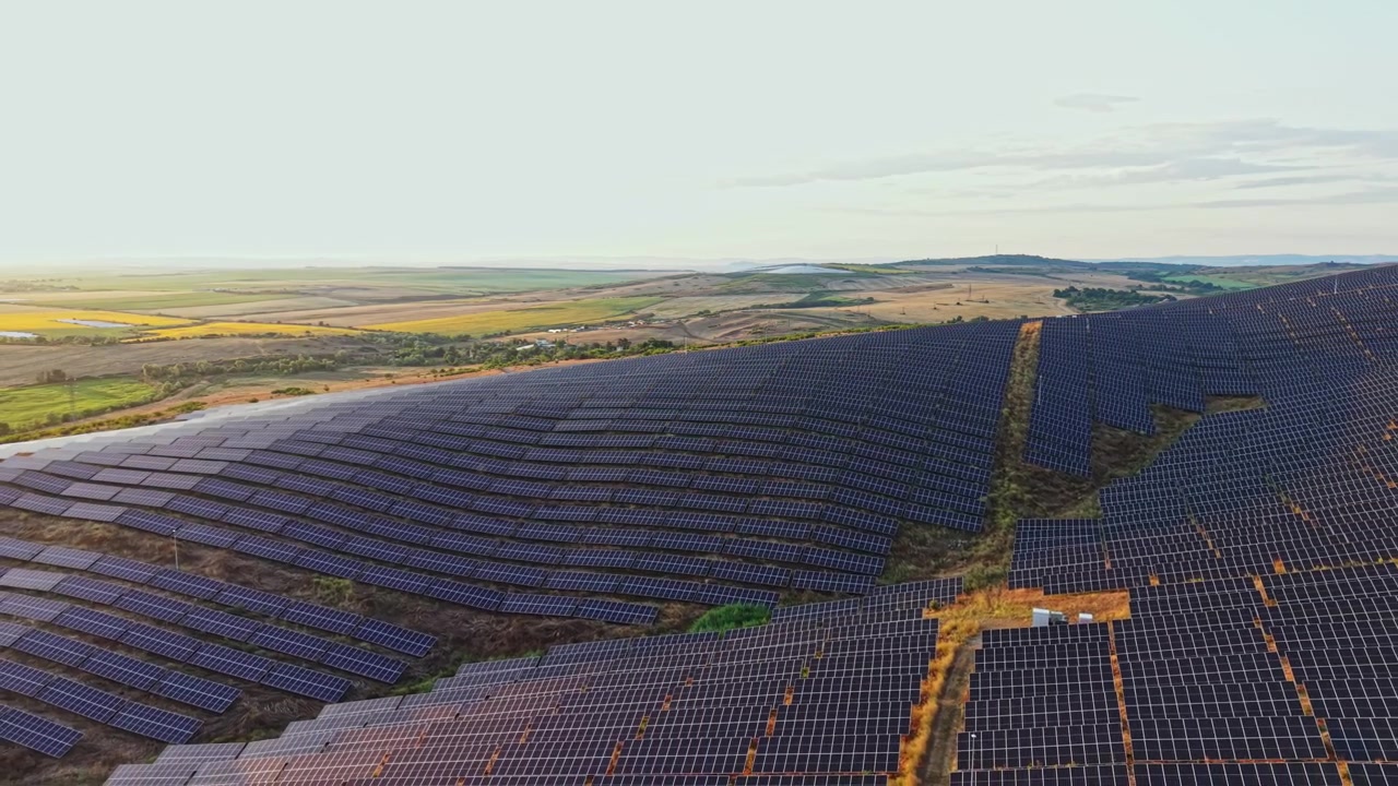 Solpaneler dækker et stort område på en mark ved solnedgang og leverer vedvarende energi i et landbrugslandskab.