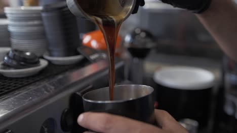 barista pouring cold coffee in cafe behind counter making a frappe