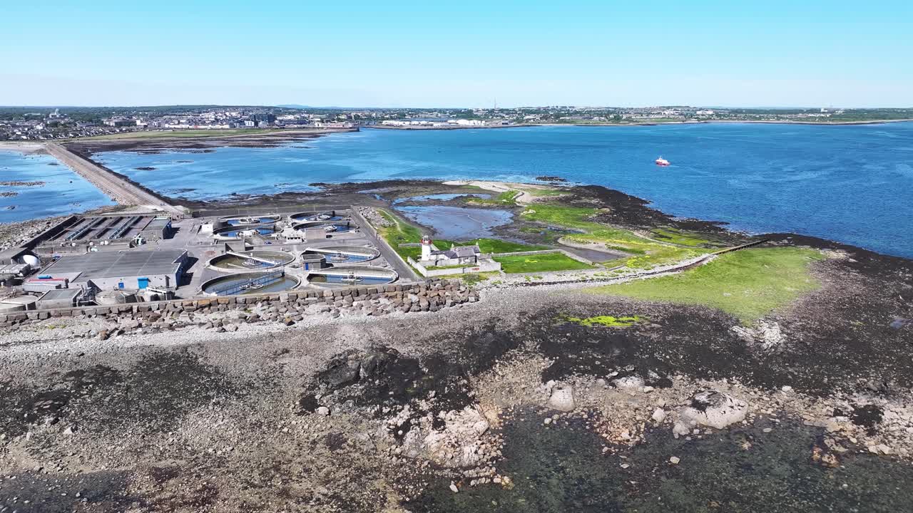 Aerial view of Galway lighthouse on rocky shore, bright day in Ireland