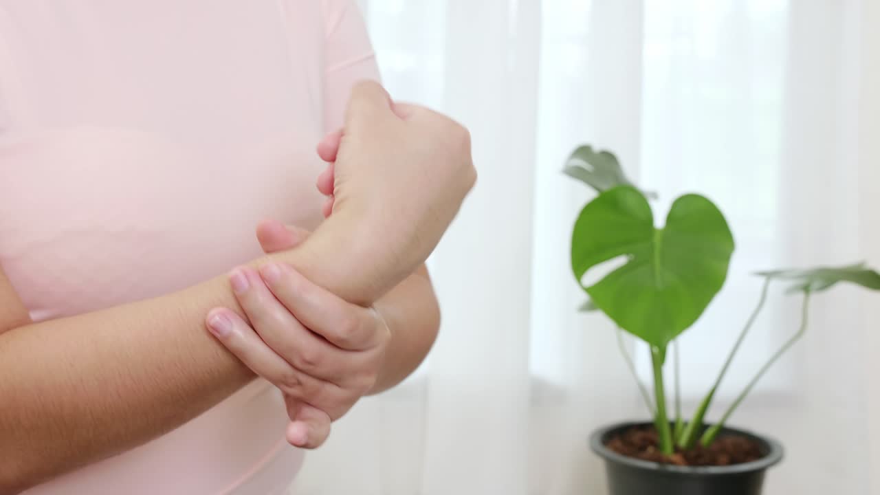 손목에 반사요법을 하고 손목을 회전시켜 업무로 인한 통증을 줄이기 위해 신체 운동을 하는 아시아 여성