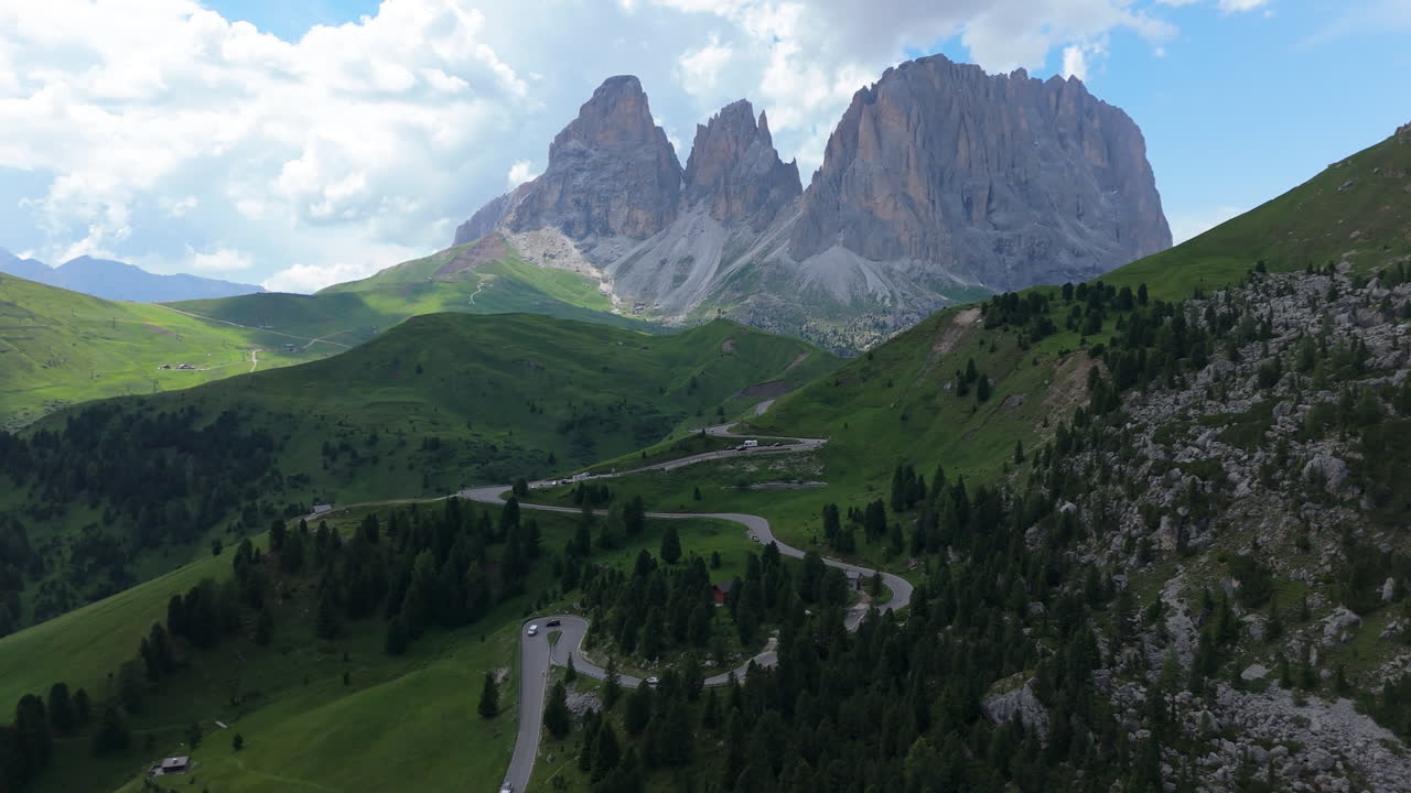 Scenic drone view over alpine meadows, forests and villages leading to majestic Dolomites peaks in summer light and clear sky