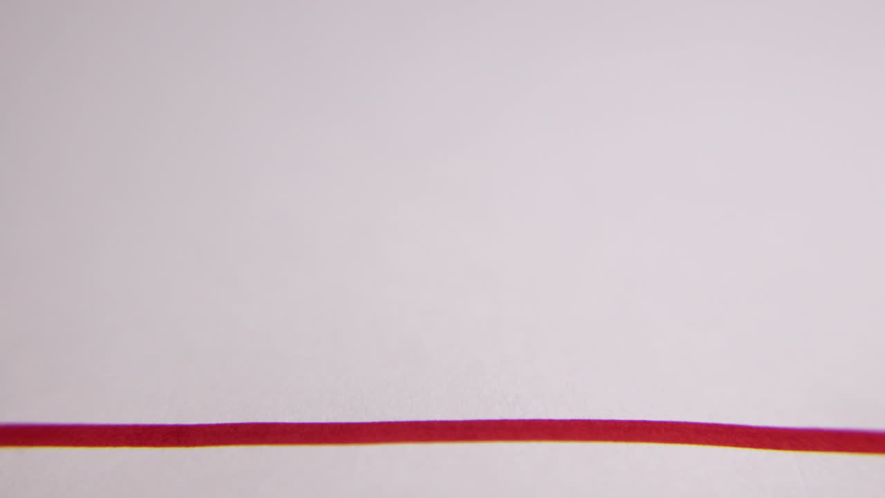 línea roja dibujada con un pincel rojo sobre una hoja de papel en blanco