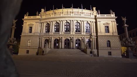 the maginificent concert hall of rudolfinum with bright facade in prague, czechia on an empty square of paved stones at night, during a covid-19 lockdown and no people anywhere, zooming shot