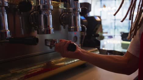 Hands-of-mixed-race-male-barista-wearing-an-apron-preparing-takeaway-coffee