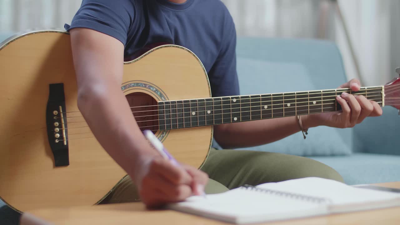 primer plano de un compositor asiático con una guitarra que tiene dolor de cabeza mientras compone música en casa