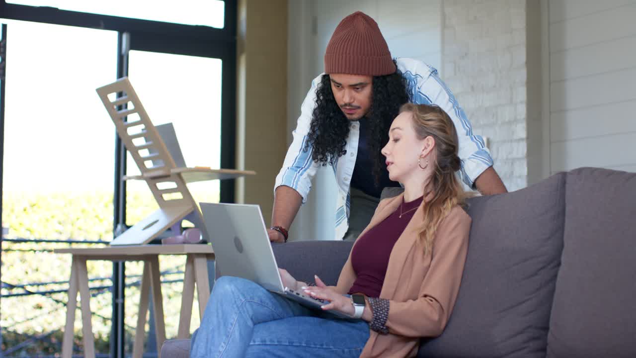 In fase di revisione, diversi colleghi che digitano e indicano lo schermo mentre un uomo osserva il laptop nella sala relax dell'ufficio