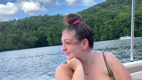 young woman happy, smiling and laughing, enjoying boat ride with wind blowing in her face, fun day