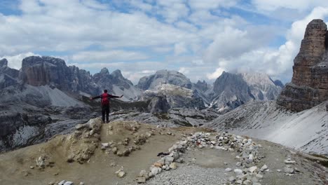 A-hiker-is-standing-alone-in-the-mountains-and-feeling-achievement-and-success-after-an-adventures-hike-in-the-Dolomites-in-North-Italy