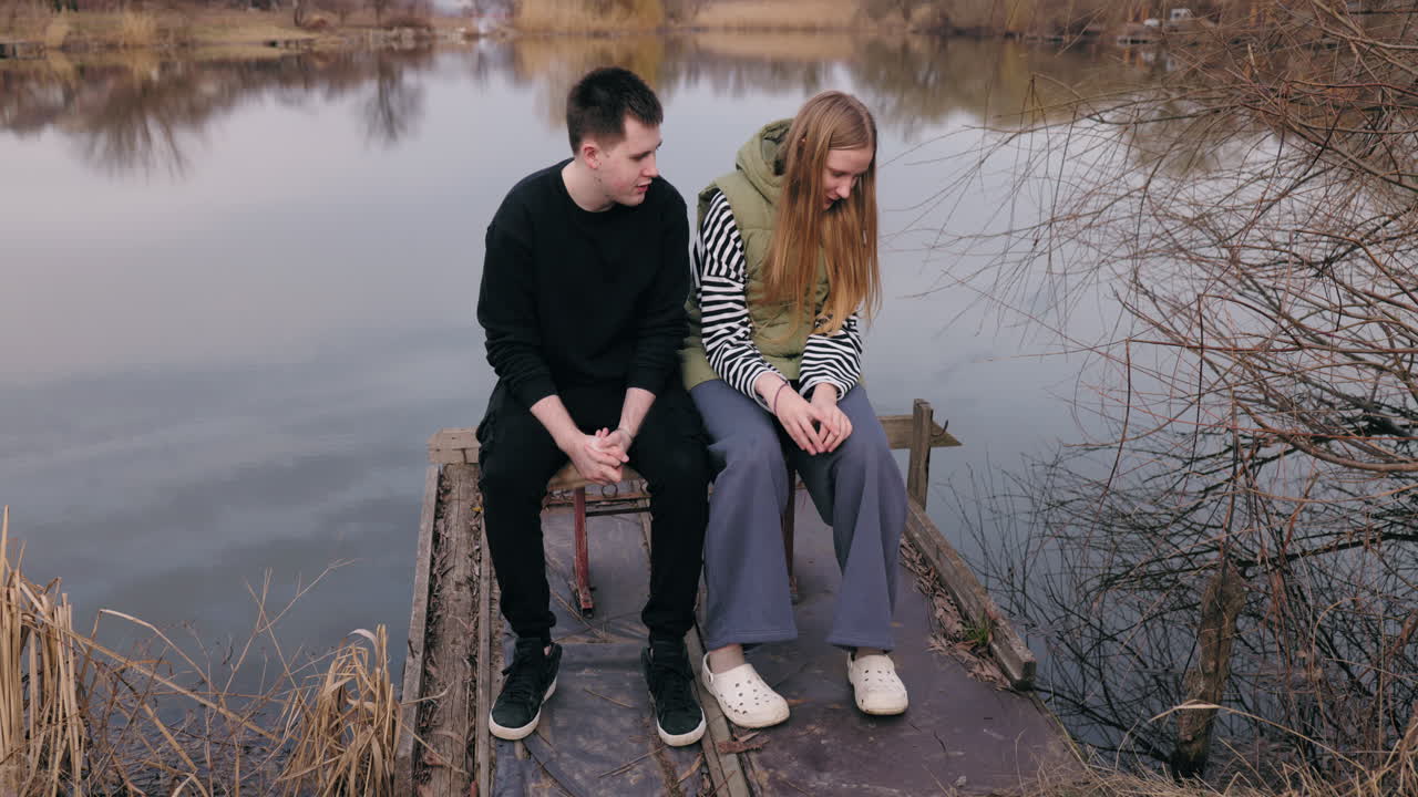 Couple Sitting on a Pier by a Lake