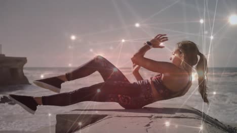 Glowing-network-of-connections-against-caucasian-woman-performing-abs-exercise-at-the-beach