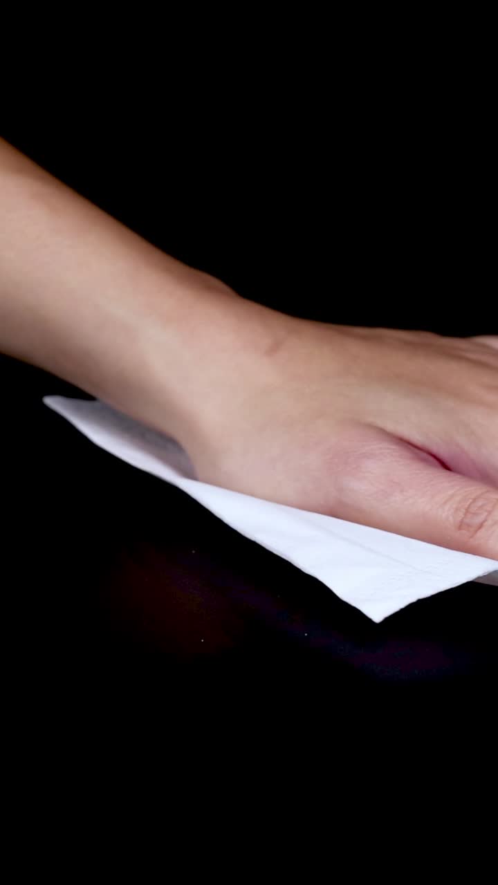 A hand cleans a surface using a cloth