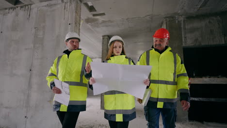 young female architect and two male civil engineers are checking under-construction building