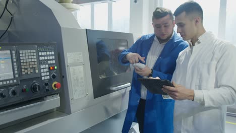 industrial employees with tablet inspecting factory equipment