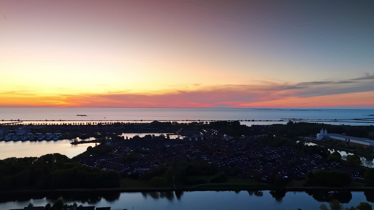 Scenery of dark village on the water at dusk time. Beautiful colors in the sky at sunset over the waterscape.