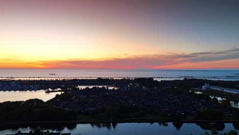 scenery of dark village on the water at dusk time. beautiful colors in the sky at sunset over the waterscape.