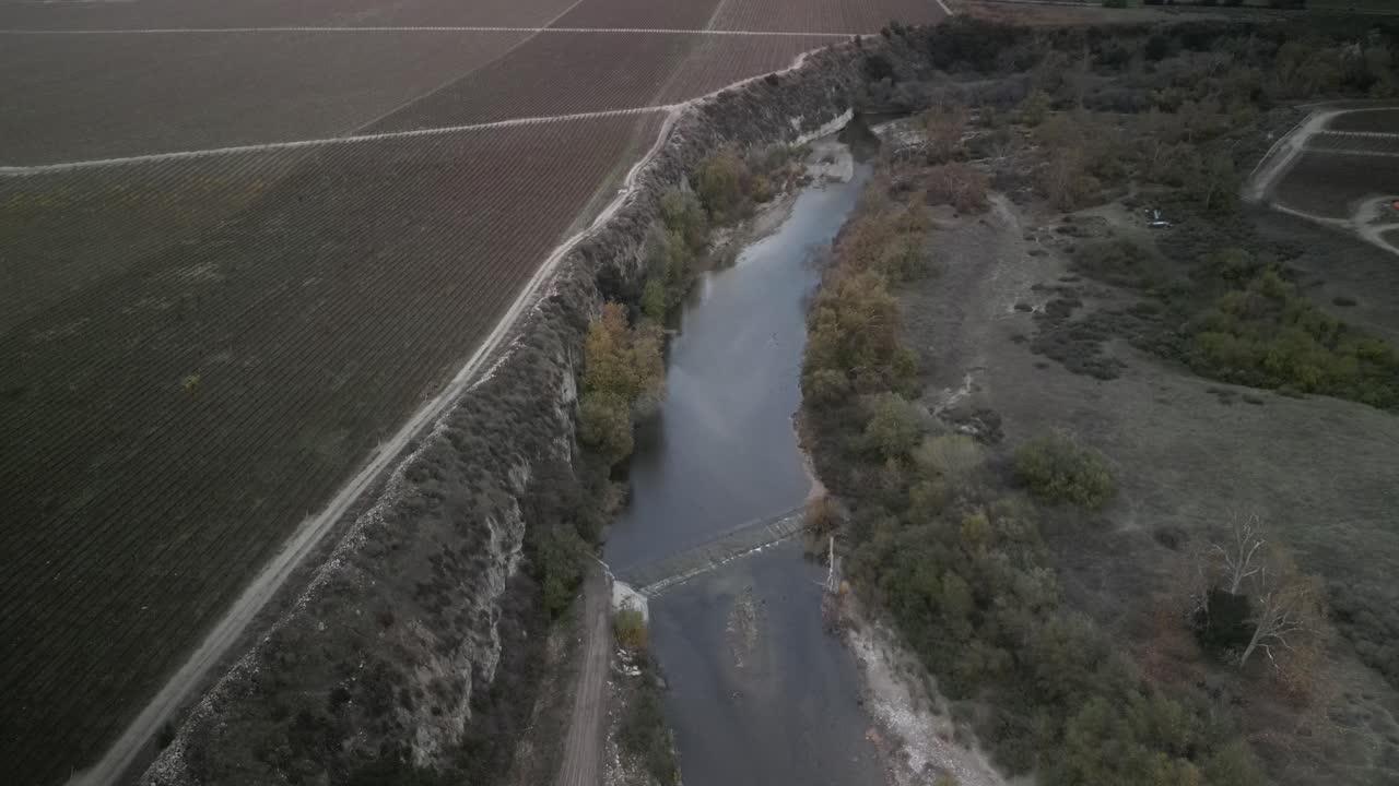vista aérea capturando el río arroyo seco serpenteando a través del paisaje agrícola de greenfield, california, bajo un cielo nublado y colinas suaves, drone descendiendo en cámara lenta