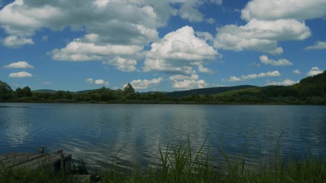 Timelapse-of-lakeside-scene-with-a-vibrant-blue-sky-and-fluffy-clouds