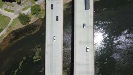 Vista-De-Pájaro-De-Dos-Puentes-Paralelos-Llenos-De-Autos-Que-Cruzan-La-Hermosa-Laguna,-San-Mateo