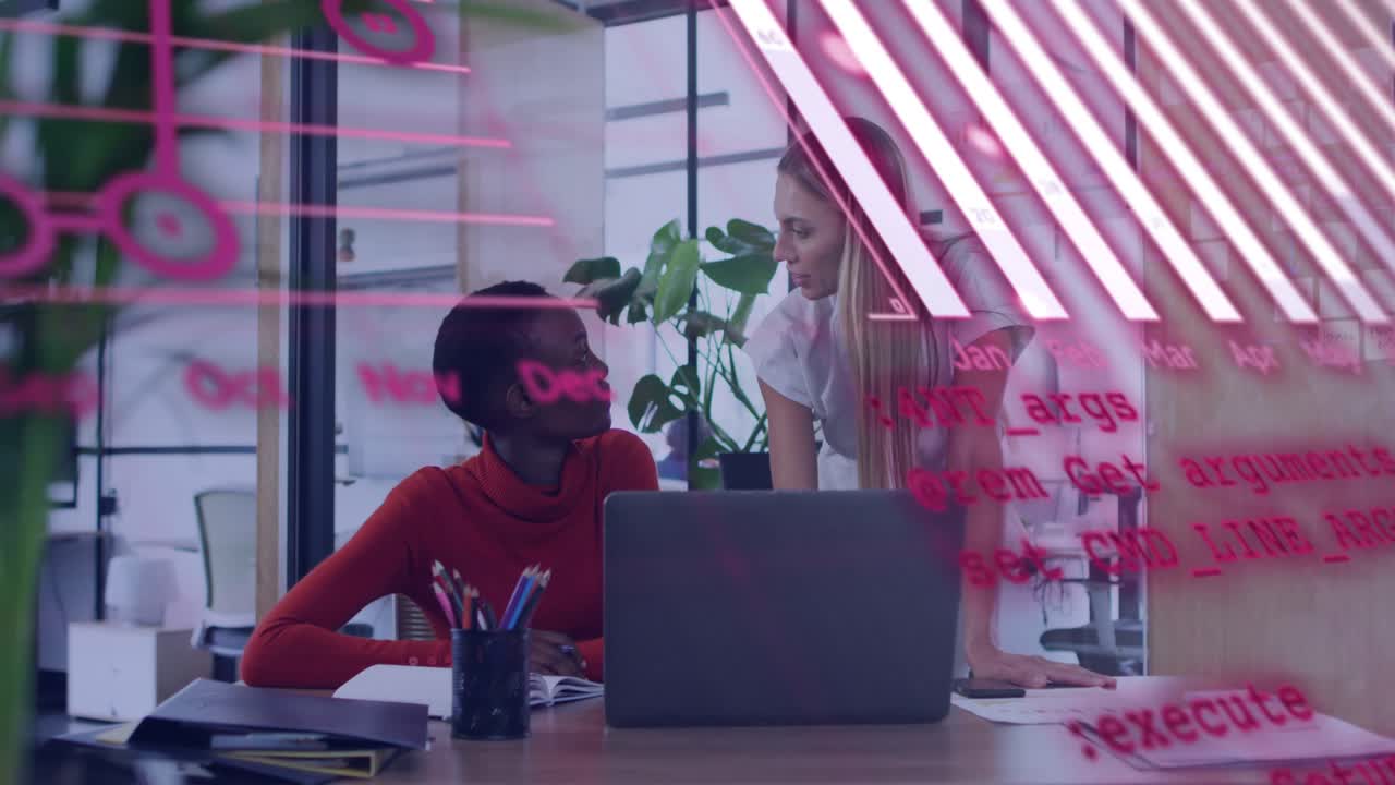 2 women reviewing work in office colleague leaning in pointing at laptop while pink charts flowing
